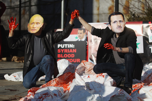 Actors wearing masks of Syrian President Bashar al-Assad and Russian Prime Minister Vladimir Putin perform with body bags during a demonstration outside United Nations headquarters on January 24, 2011 in New York City. 