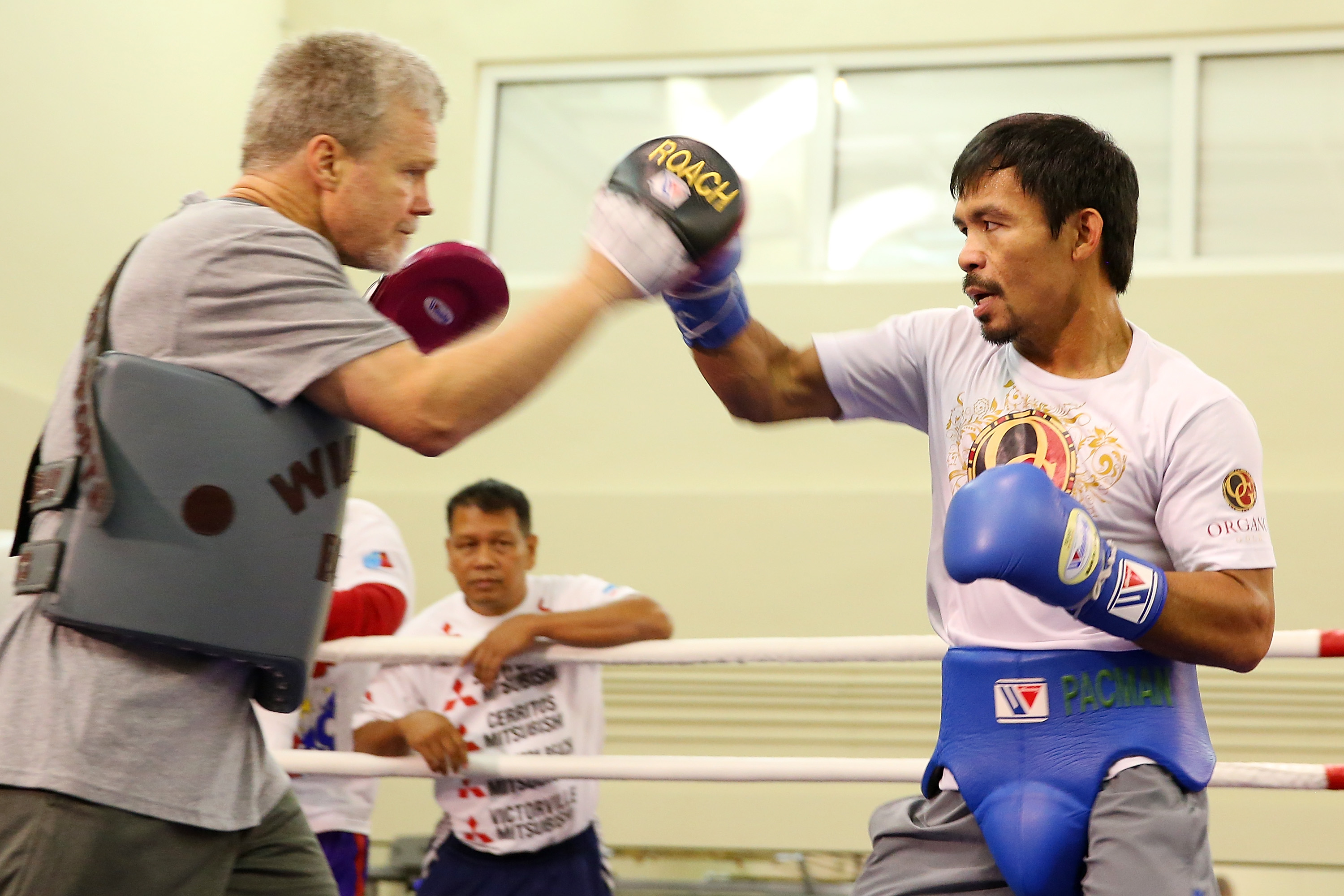Freddie Roach works the mitts with Manny Pacquiao during a workout session. (Getty)