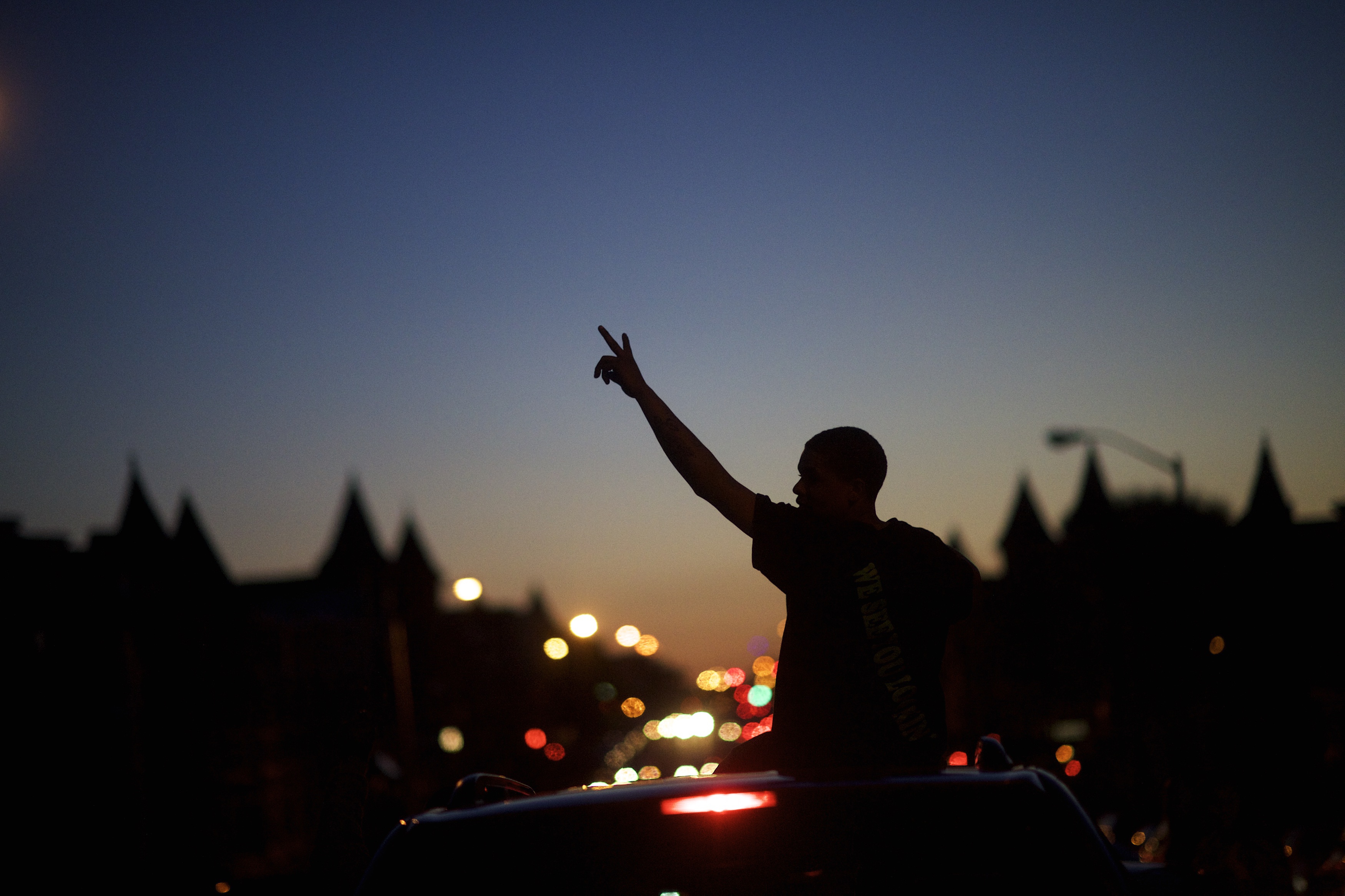 Young people in cars drive towards a phlanx of Baltimore riot police honking their horns and raising their hands with peace signs. (Getty)