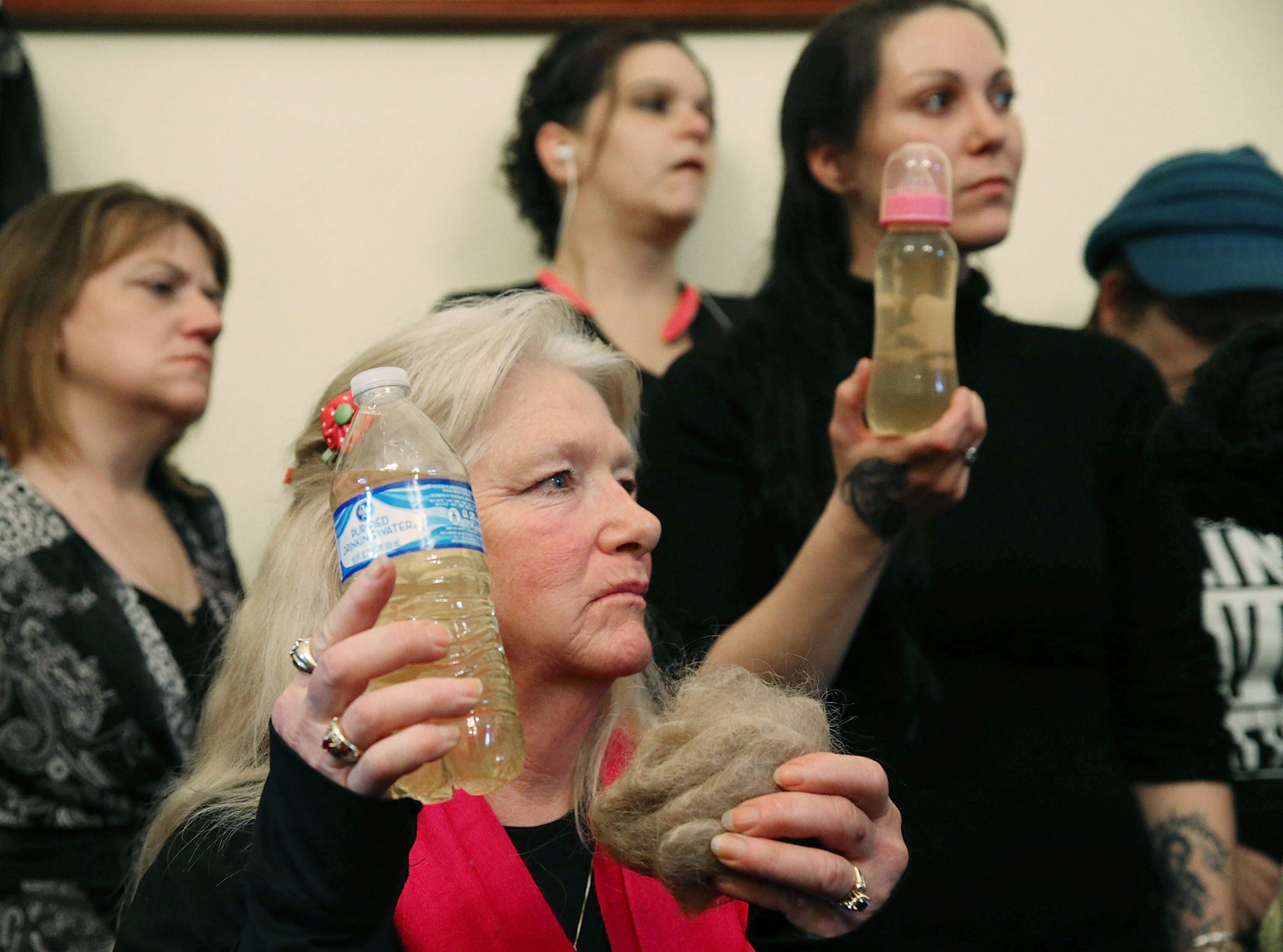 Flint resident Gladyes Williamson holds a bottle full of contaminated water, and a clump of her hair, alongside Jessica Owens, holding a baby bottle full of contaminated water, during a news conference after attending a House Oversight and Government Reform Committee hearing on the Flint, Michigan water crisis on Capitol Hill February 3, 2016 in Washington, DC.  (Getty)