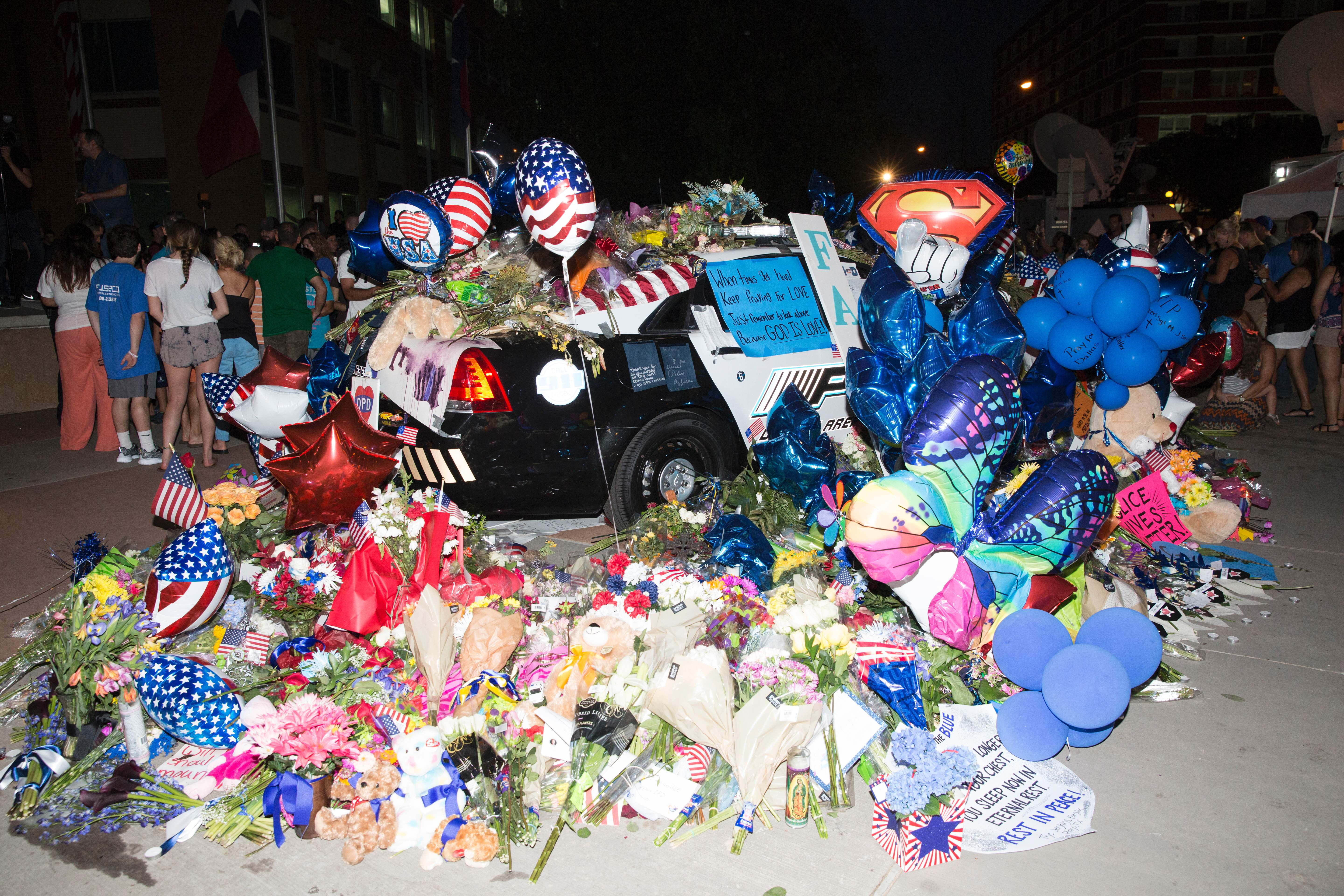 Flower, cards, balloons, and candles pile on top of police cruisers outside the Police Headquarters memorial for officers killed in the recent sniper attack in Dallas, Texas on July 10, 2016. (Getty)