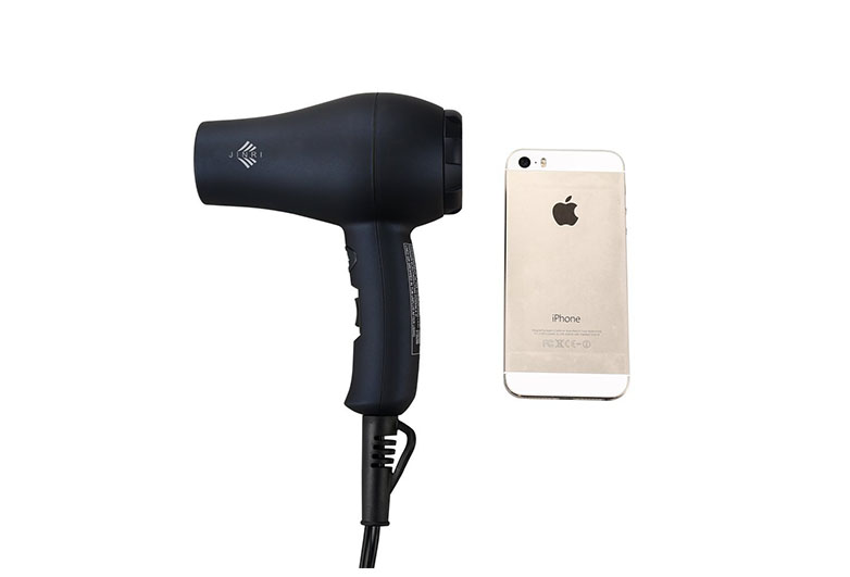 Black mini hair dryer next to iphone for scale