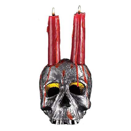Silver skull holding two red candles