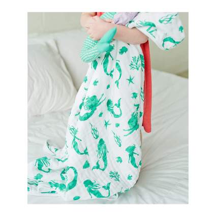 toddler with white and teal mermaid blanket