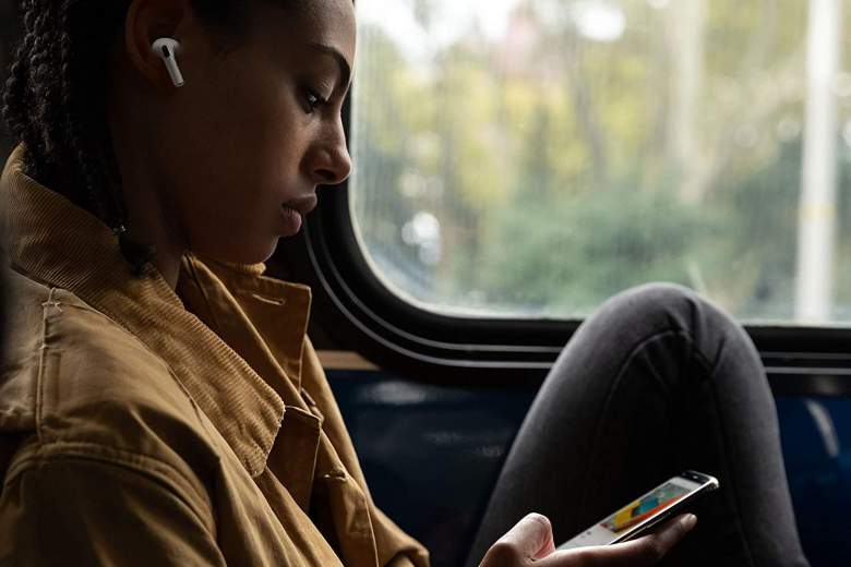 Woman on bus listening to noise cancelling earbuds with iPhone