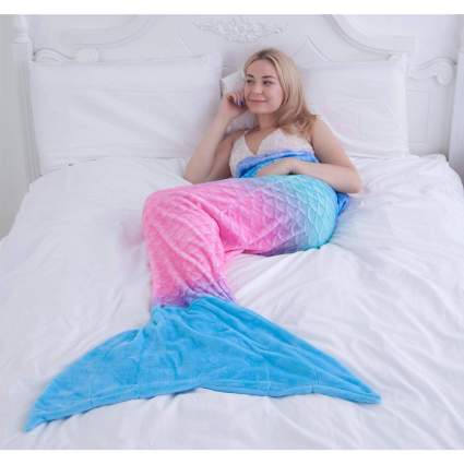 woman on bed in colorful mermaid tail blanket