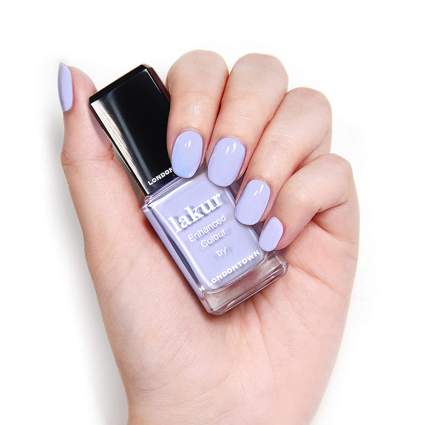 Hand with light purple polish and nail polish bottle