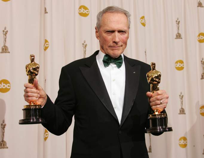 Clint Eastwood holding Oscars.