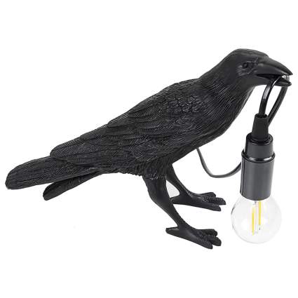 black raven holding a light bulb