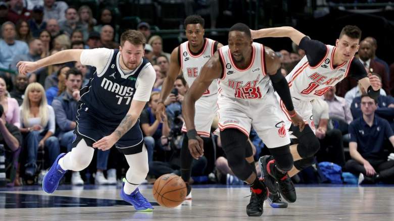 Luka Doncic #77 of the Dallas Mavericks scrambles for the ball against Bam Adebayo #13 and Tyler Herro #14 of the Miami Heat.