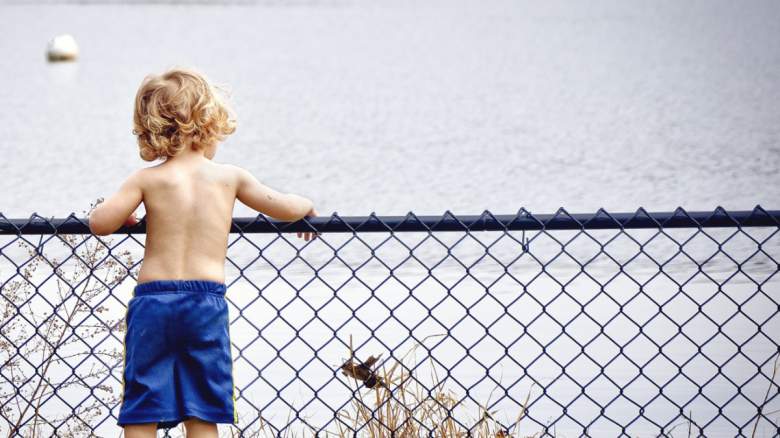 A toddler standing by a lake.