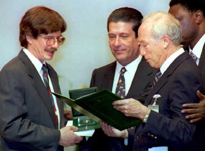 James Earl Carter III (L), on behalf of his father the former US President Jimmy Carter, is bestowed the UNESCO Peace Prize by former Canadian Prime minister Pierre Eliott Trudeau (R) as UNESCO secretary general Federico Mayor (C) looks on during a ceremony.