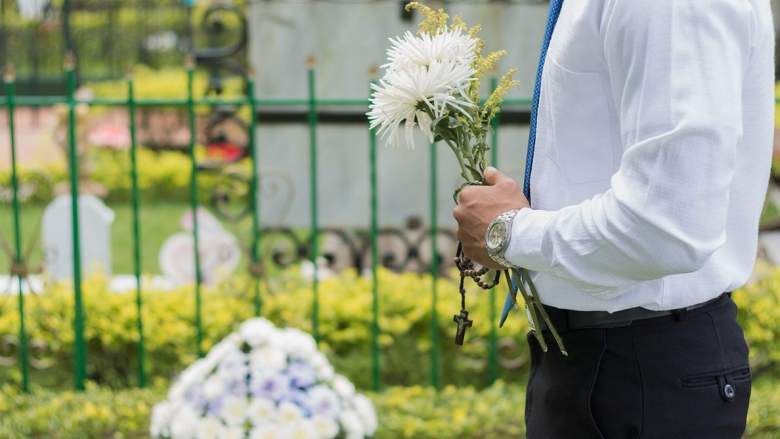 Man carries flowers to a grave