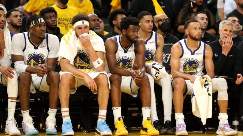 Stephen Curry and Jordan Poole sit with teammates on the Golden State Warriors Bench.