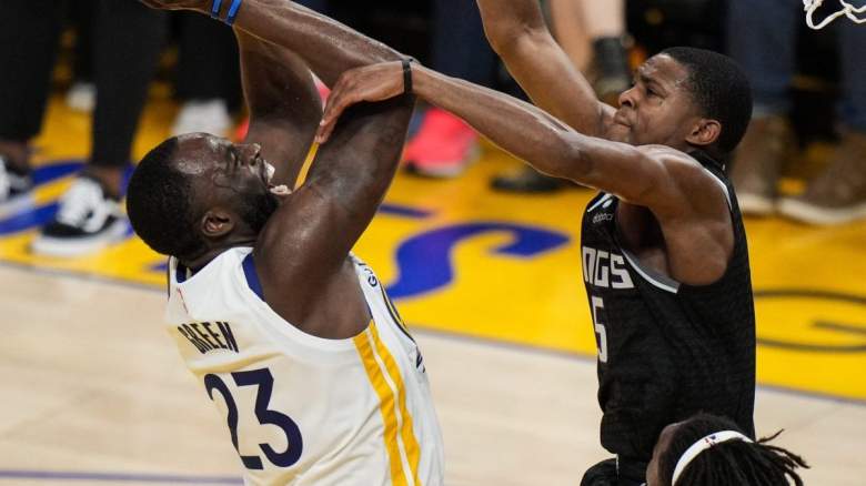 Draymond Green of the Golden State Warriors is defended by De'Aaron Fox of the Sacramento Kings.