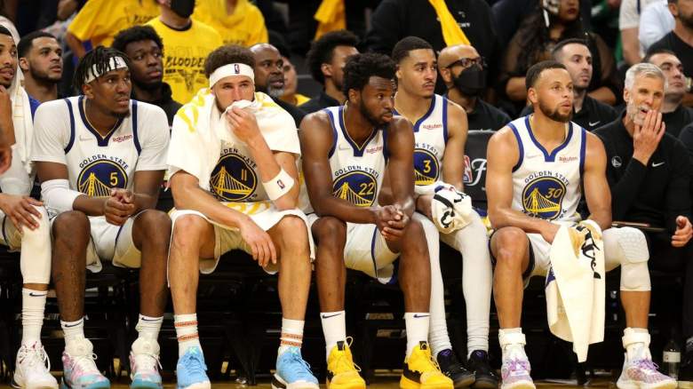 Stephen Curry and Andrew Wiggins sit with their Golden State Warriors teammates.