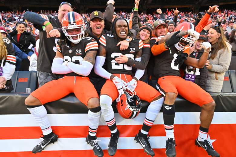 3 Browns players celebrating with fans in the stands.