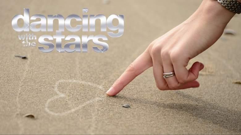 A woman drawing a heart in the sand.