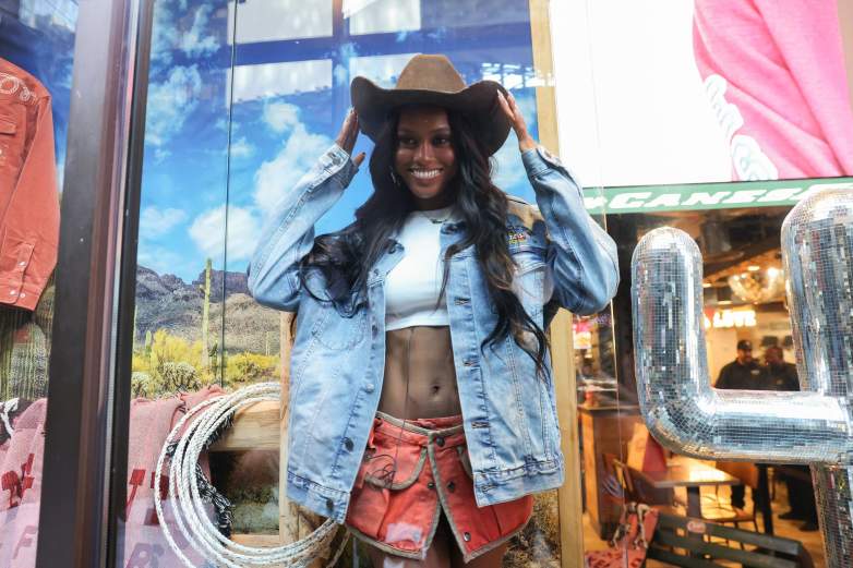 Ciara Miller stands out of Raising Cane's Time Square location while modeling items from the brand's new Western clothing line.