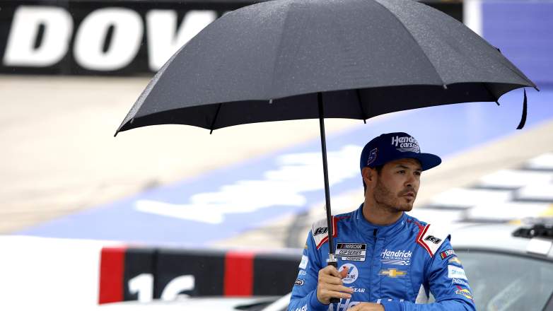Kyle Larson stands under umbrella during NASCAR rain delay at Dover Motor Speedway