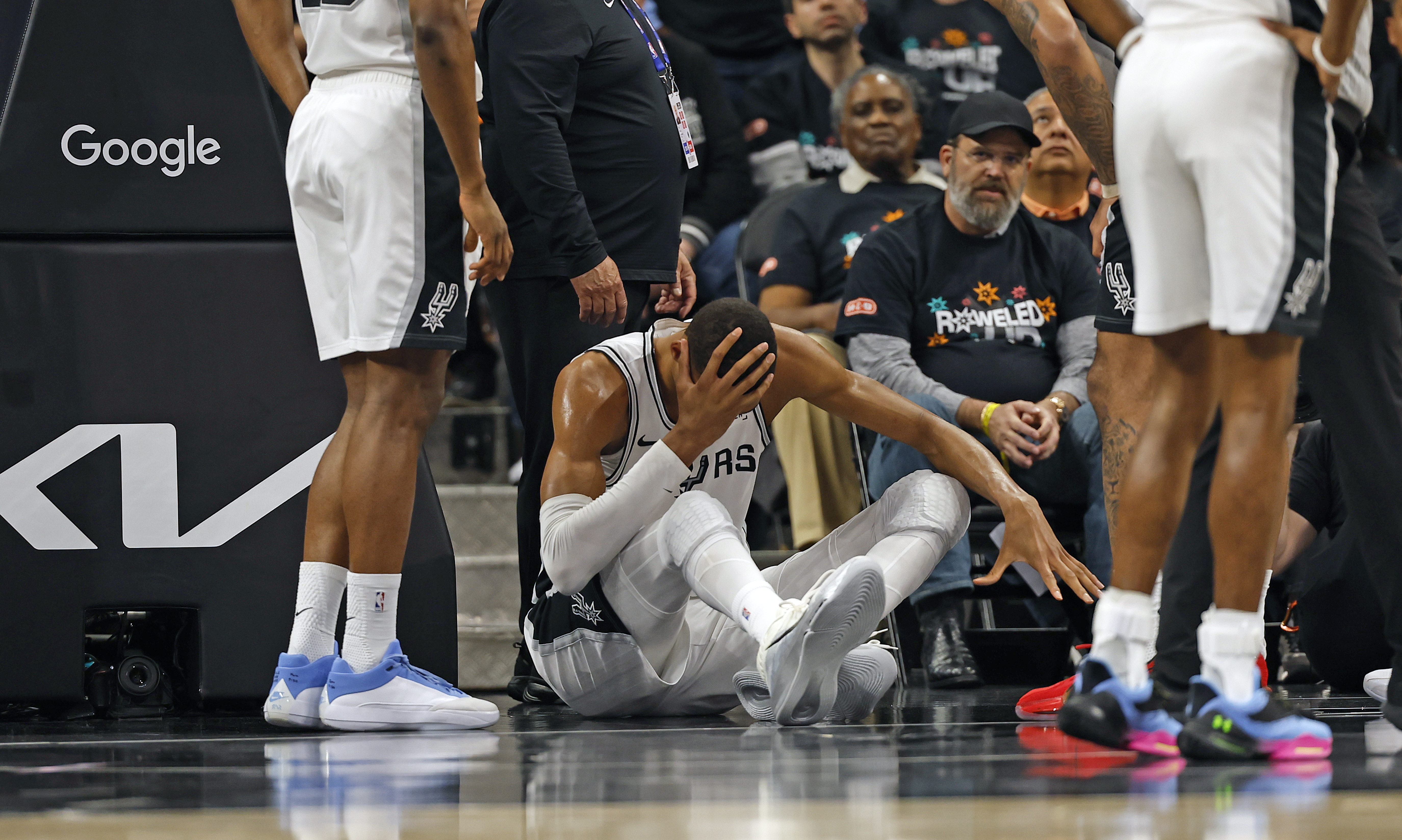 Victor Wembanyama #1 of the San Antonio Spurs holds his head after falling to the court