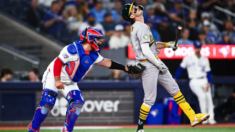 Alejandro Kirk #30 of the Toronto Blue Jays tags out Jacob Wilson #5 of the Athletics after he swings at a pitch in the dirt in the ninth inning of their MLB game at Rogers Centre on March 27, 2026 in Toronto, Ontario, Canada.