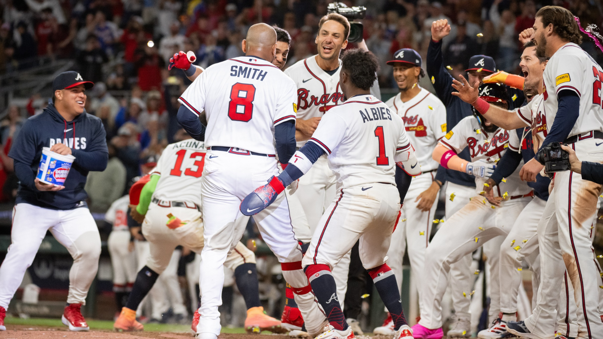 Dominic Smith #8 of the Atlanta Braves approaches home plate and teammates Ronald Acu&ntilde;a Jr. #13, Matt Olson #28, Ozzie Albies #1, Mike Yastrzemski #18, and Austin Riley #27 after hitting a game-winning grand slam home run in the bottom of the ninth inning of a game against the Kansas City Royals at Truist Park on March 28, 2026 in Atlanta, Georgia. (Photo by Edward M. Pio Roda/Getty Images)