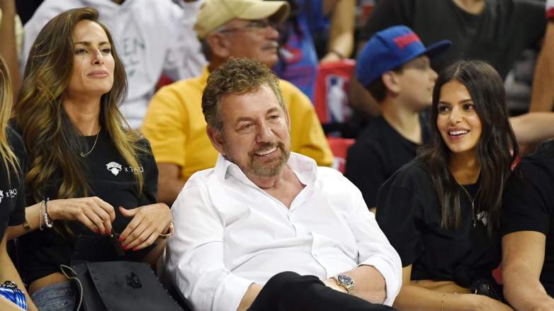 James Dolan sitting courtside at a Knicks game with fans in the background