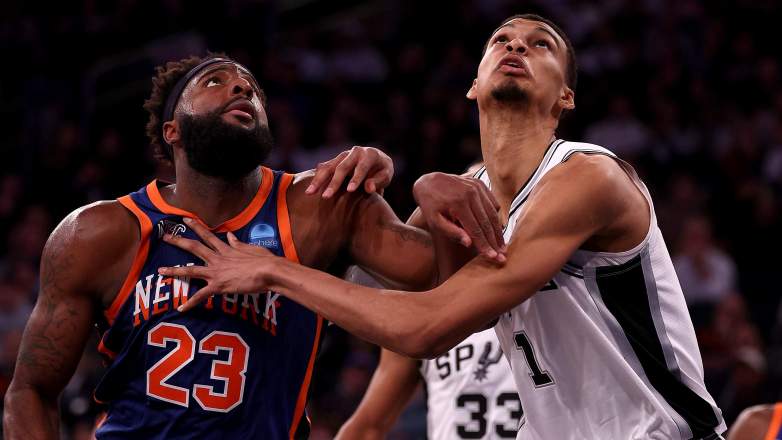 Mitchell Robinson and Victor Wembanyama fight for rebounding position during a Knicks-Spurs game.