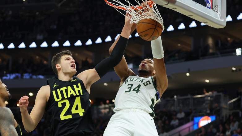 Utah Jazz center Walker Kessler jumps to challenge Milwaukee Bucks forward Giannis Antetokounmpo at the basket during an NBA game.