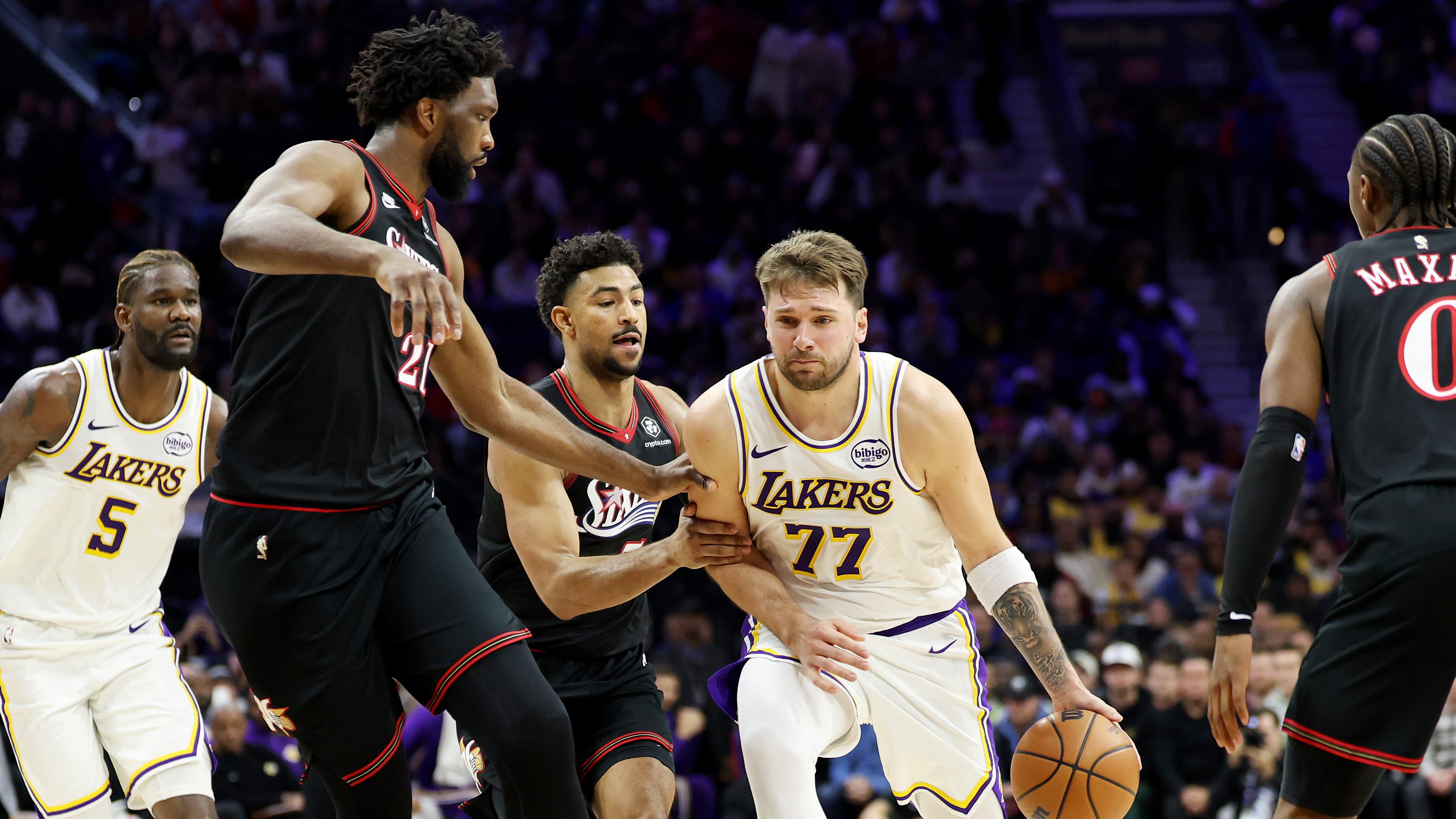 Los Angeles Lakers guard Luka Doncic dribbles between Philadelphia 76ers defenders during an NBA game amid reports linking the Lakers to free-agent guard Quentin Grimes.