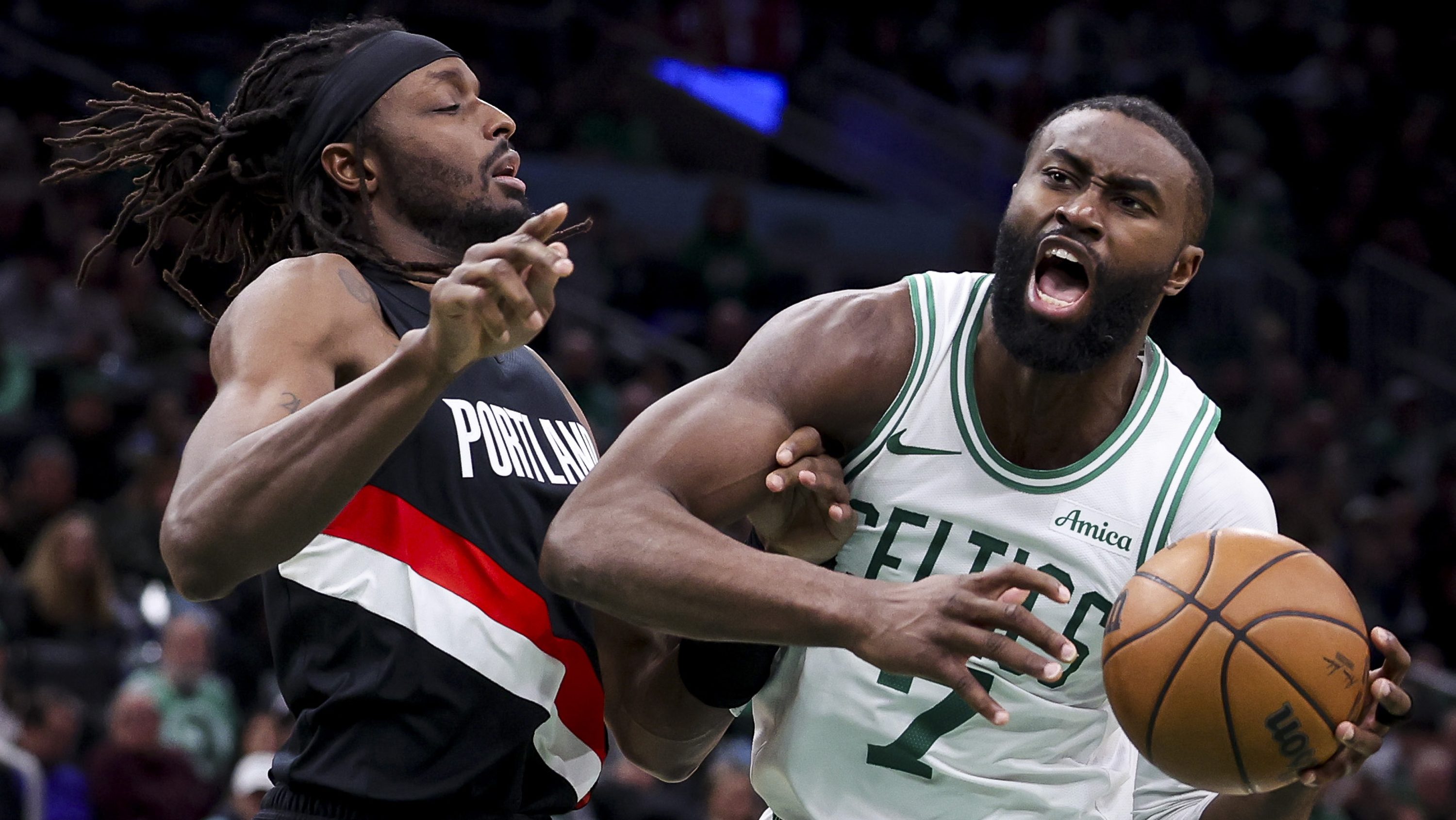 Boston Celtics star Jaylen Brown drives to the basket against Portland Trail Blazers forward Jerami Grant during an NBA game.