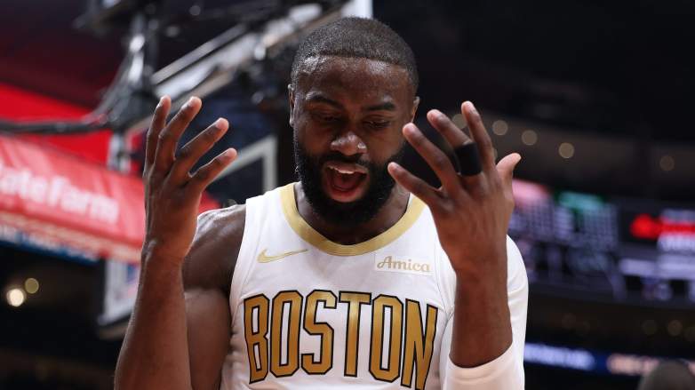 Boston Celtics forward Jaylen Brown reacts during an NBA game, raising both hands while wearing the team's white jersey as trade speculation continues around his future.