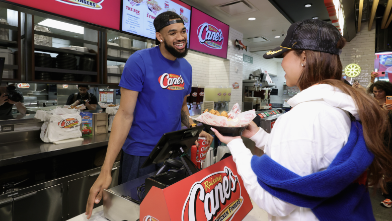 New York Knicks star Karl-Anthony Towns serves a meal to fiancée Jordyn Woods during a celebratory shift at Raising Cane's flagship restaurant in Times Square following the team's NBA championship.