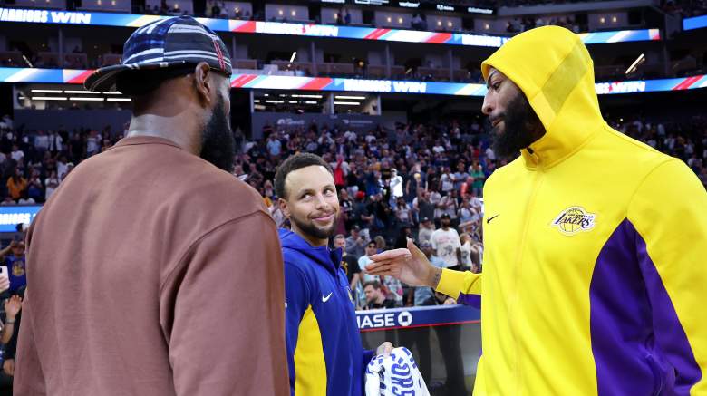 Anthony Davis approaches Stephen Curry as LeBron James stands nearby following a Warriors-Lakers game.