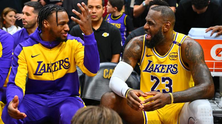 Bronny James gestures while talking with his father, LeBron James, on the Los Angeles Lakers bench.