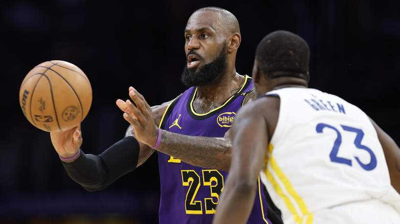 LeBron James passes the ball while defended by Draymond Green during a Lakers-Warriors game.