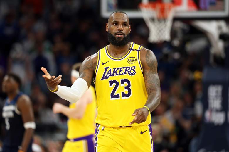 LeBron James gestures during a Los Angeles Lakers game as Anthony Edwards is blurred in the background.