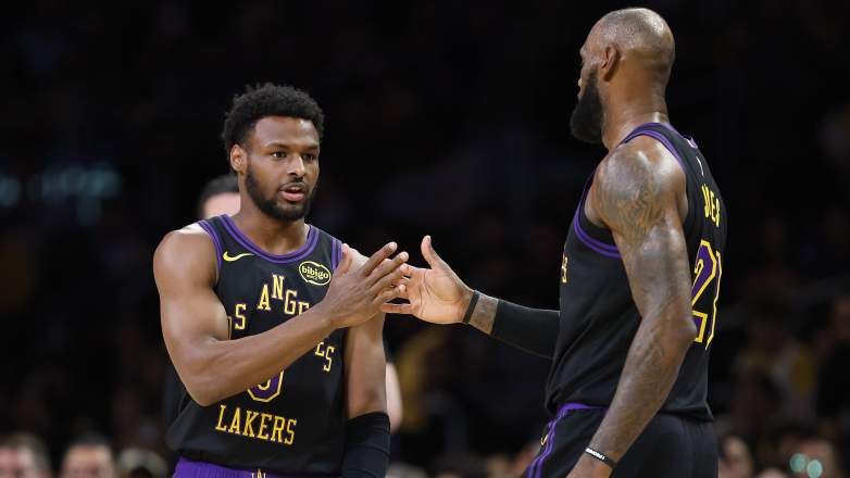 Bronny James exchanges a handshake with LeBron James during a Los Angeles Lakers game.
