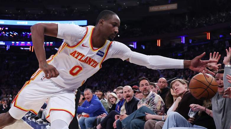 Jonathan Kuminga reaches for a loose ball near the courtside seats while playing for the Atlanta Hawks.