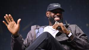 LeBron James smiles and gestures while holding a microphone at Fanatics Fest in New York.