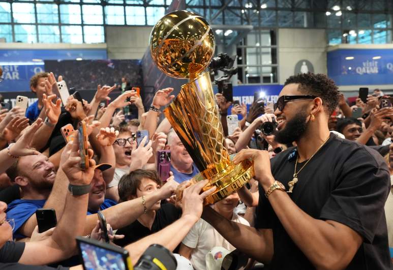 Karl-Anthony Towns smiles as Knicks fans touch the Larry O'Brien Trophy during Fanatics Fest after New York's NBA championship.