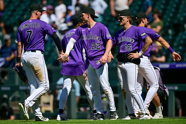 DENVER, COLORADO - JULY 18: Mickey Moniak #22, Cole Carrigg #16, and TJ Rumfield #7 of the Colorado Rockies celebrate after the win against the Cincinnati Reds at Coors Field on July 18, 2026 in Denver, Colorado. (Photo by Dustin Bradford/Getty Images)