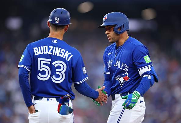 TORONTO, ON - JULY 20: George Springer #4 of the Toronto Blue Jays celebrates with First Base Coach Mark Budzinski #53 after hitting a single in the fourth inning during a game against the Tampa Bay Rays at Rogers Centre on July 20, 2026 in Toronto, Ontario, Canada. (Photo by Vaughn Ridley/Getty Images)