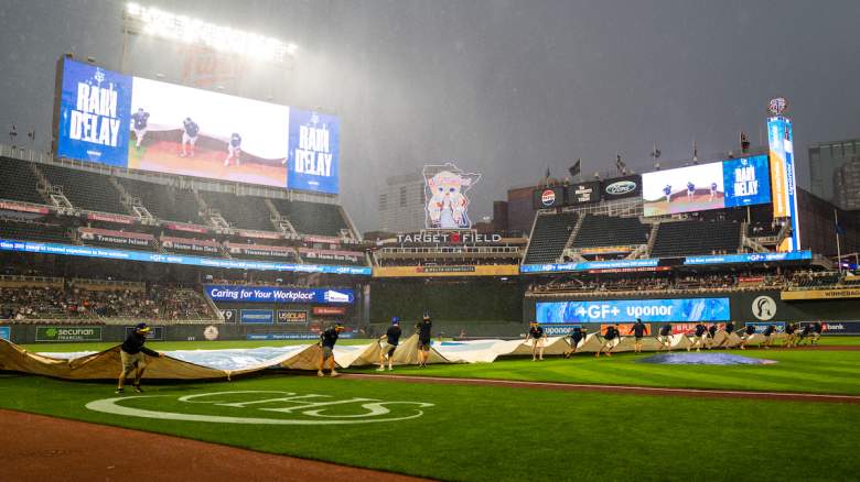 Grounds crew members pull a tarp over the infield during a rain delay