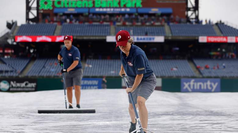 Members of the grounds crew roll water off the tarp before the start of a game