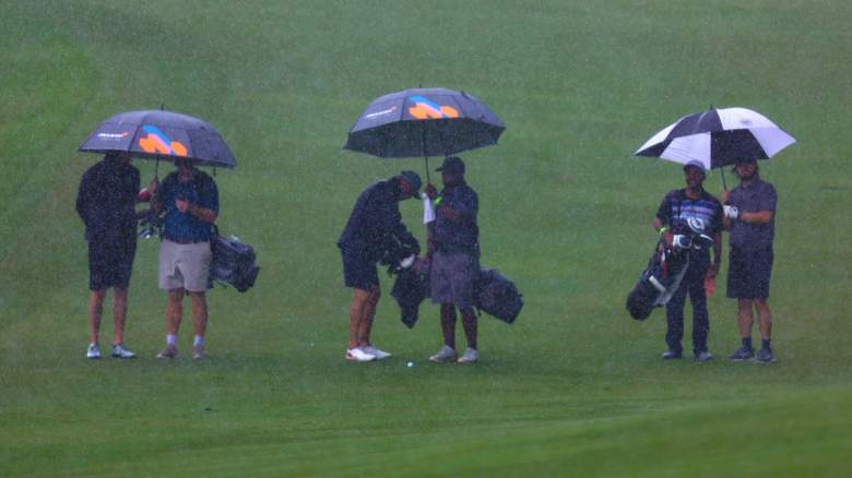 Golfers stand under umbrellas in the rain during practice before the Wyndham Championship